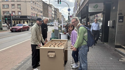 Fußgänger spielen amüsiert mit Jan Ottensmann dem Quartiersmanager Minifußball