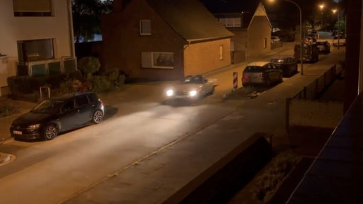 Ein weißes Auto rast in einem Wohnviertel