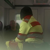 Ein Mann in Rettungsdienst-Kleidung von hinten, anonymisiert, in einem Krankenwagen.