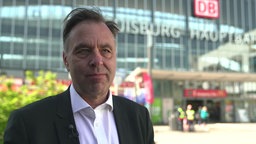 Ein Mann in Anzug steht vor dem Duisburger Hauptbahnhof 