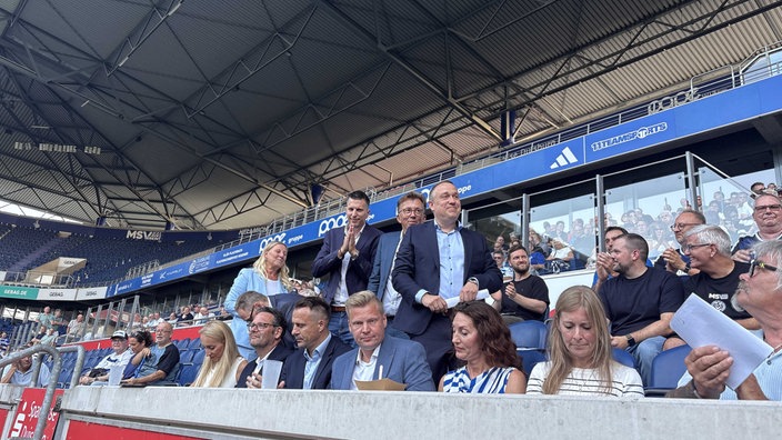 Dirk Broska, Veronika Henschel-Grontzki, Ralf Raddue, Dirk Recke und Thorsten Immel stehen auf der Tribüne und lächeln.