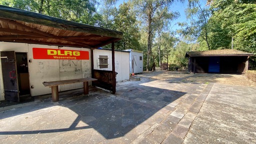 Eine Holzhütte mit einem großen Schild der DLRG darüber 