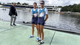 Zwei junge Männer in Ruderkleidung stehen am Rand der Regattabahn in Duisburg 