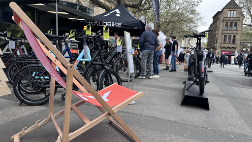 Pavillons an denen E-Bike angeboten werden. Im Vordergrund steht ein roter Liegestuhl