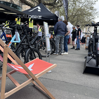 Pavillons an denen E-Bike angeboten werden. Im Vordergrund steht ein roter Liegestuhl