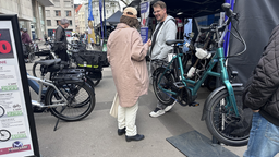 Zwei Personen unterhalten sich. Um die beiden stehen einige E-Bikes