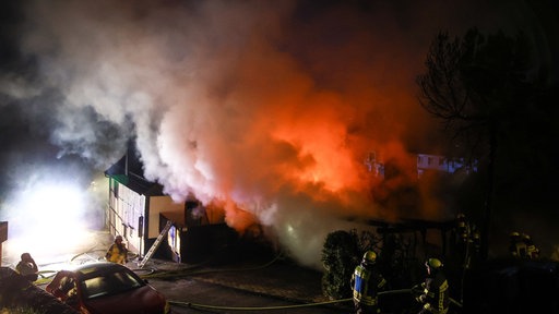 Neben einem Haus brennt ein Carport, wodurch eine große Rauhcwolke zu erkennen ist.
