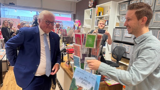 Bundespräsident Steinmeier bekommt in einer Buchhandlung in Hattingen eine Papiertüte überreicht