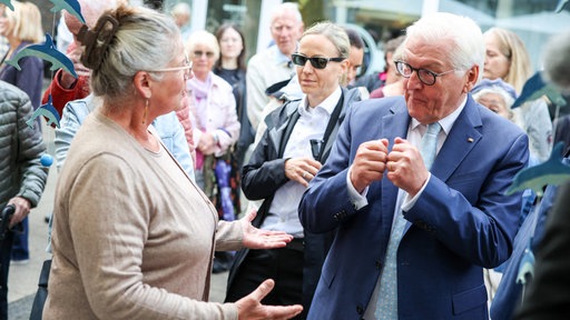 Bundespräsident Steinmeier spricht in der Hattinger Altstadt mit der Inhaberin eines Geschäfts, drumherum stehen weitere Menschen