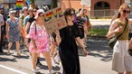 Beim CSD in Hattingen trägt eine Frau im schwarzen Kleid ein Schild, darauf steht: Love is such a terrible thing to hate.