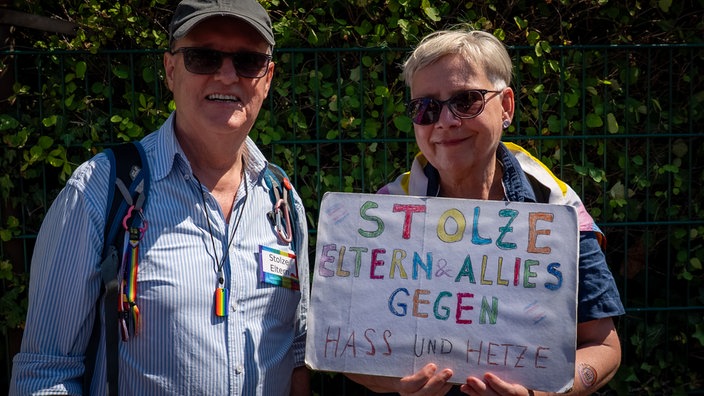 Ein Ehepaar lächelt in die Kamera. Auf ihrem Plakat beim CSD in Hattingen steht: Stolze Eltern & Allies gegen Hass und Hetze