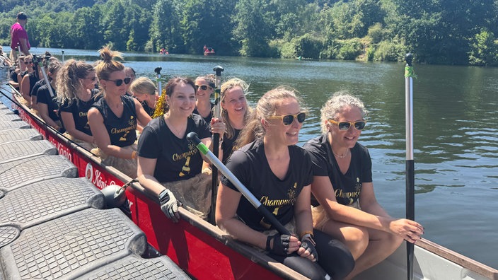 Ein Drachenboot am Ufer mit einem Frauen-Team. 