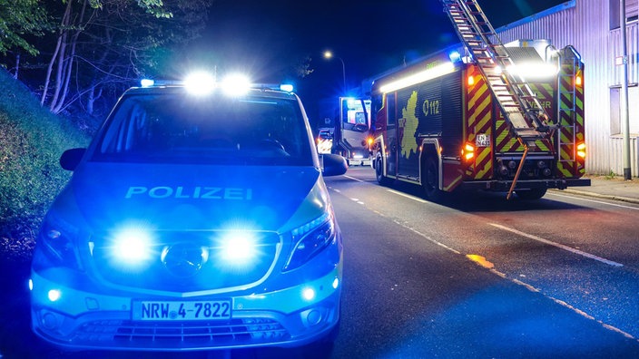 Im Vordergrund steht ein Polizeiwagen und im Hintergrund ein Feuerwehrauto.