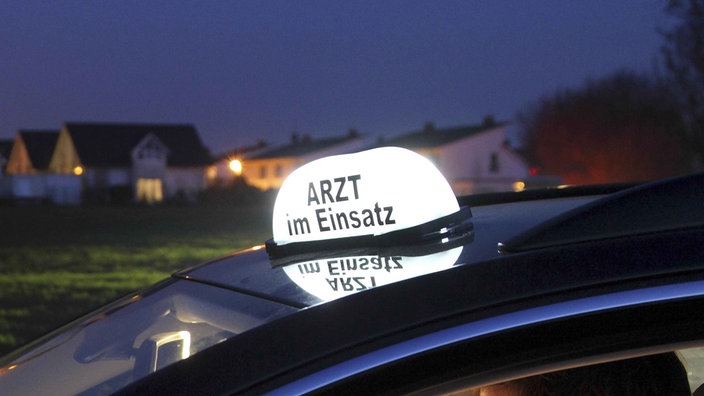 Auf einem leuchtenden Schild auf einem Autodach steht "Arzt im Einsatz"