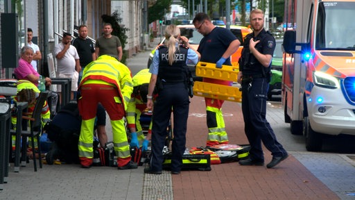 Einsatzkräfte behandeln eine Person, die auf dem Gehweg liegt.