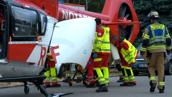 Einsatzkräfte laden eine verletzte Person in einen Hubschrauber.