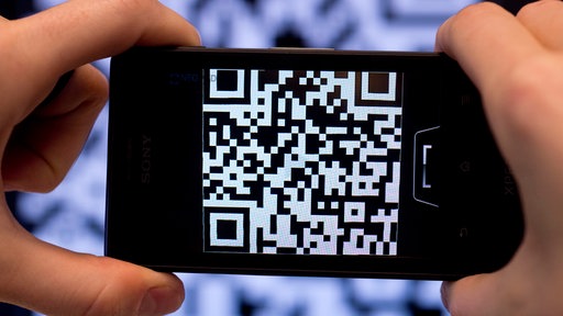 Zwei Hände, die ein Handy halten, das einen QR-Code scannt.