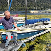 Mann schaufelt Wasserpflanze aus See.