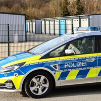 Ein Einsatzwagen der Polizei steht vor dem eingezäunten Gelände eines Garagenhofs in Gevelsberg.