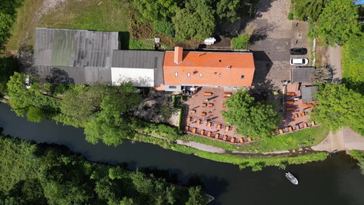 Vogelperspektive eines Grundstücks mit Biergarten, Steinhaus und angrenzendem Fluss