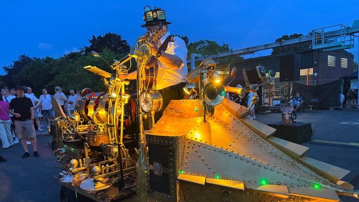 Ein Mann steht auf seiner Miniatur-Nautilus und spielt Musik.