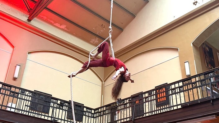 Artistin Anna Abrams hängt waagerecht an einem Vertikalseil von der Decke der Lohnhalle.