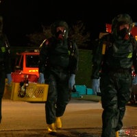Drei Personen in Schutzanzügen. Zwei davon tragen einen Korb in dem, Einsatzmaterialien liegen. 