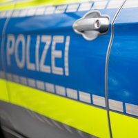 Auf der Seite eines Polizeiautos stehen das Wort "Polizei" und ein Wappen des Landes NRW