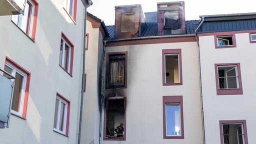 Brandspuren an der Fassade und kaputte Fenster zeigen die Folgen eines Feuers in einem mehrstöckigen Wohngebäude in Gelsenkirchen.