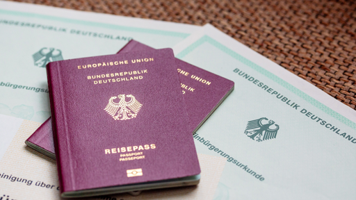 wei deutsche Reisepässe liegen auf Einbürgerungsurkunden der Bundesrepublik Deutschland sowie einem Einbürgerungstest