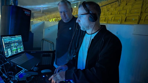 DJ Sven Pocivalnik am Mischpult in der Gelsenkirchener Eishalle, daneben steht ein weiter DJ.