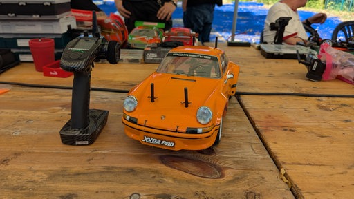 Ein orangenes Modellauto auf einem Tisch.