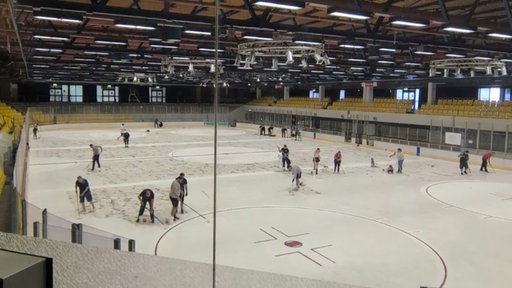 Blick in die Gelsenkirchener Eishalle: Mehrere Menschen bereiten die Eisfläche und das Halleninnere für die geplante Wiedereröffnung vor.