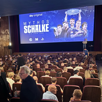Ein gefüllter Kinosaal, helle Beleuchtung und eine Leinwand mit der Aufschrift "Mythos Schalke" im Hintergrund
