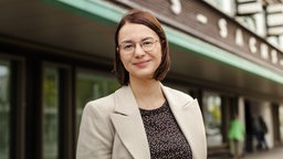 Eine Frau mit dunklem Oberteil und hellgrauem Jacket steht vor dem Gelsenkirchener Hans-Sachs-Haus