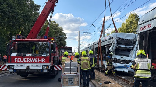 Ein Feuerwehrkran hebt die beschädigte Straßenbahn von den Schienen