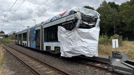 Eine der am Unfall beteiligten Straßenbahnen steht mit einer Folie über dem zerstörten Führerhaus auf einem Abstellgleis