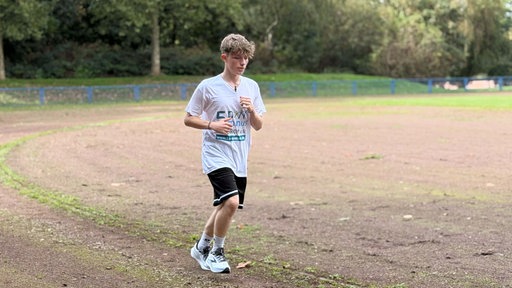 Teenager Florian läuft über einen Sportplatz