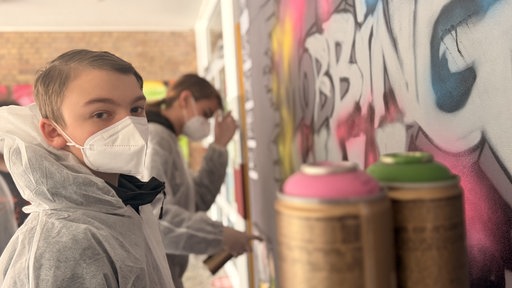Schüler sprühen ein Graffiti