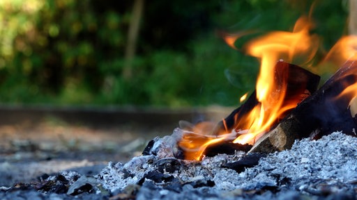 Nahaufnahme eines brennenden Grillfeuers mit glühender Holzkohle.