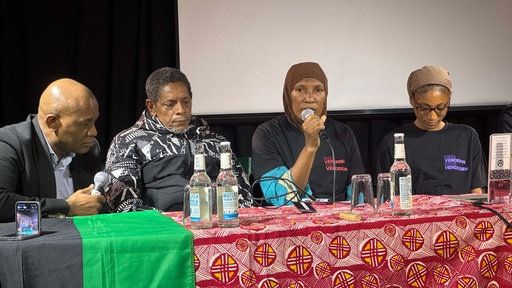 Die Familie von Ibrahima Barry sitzt an einem Podium mit Mikrofon.
