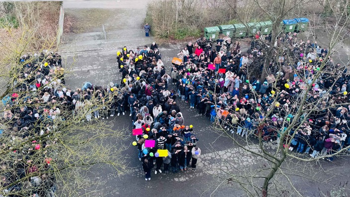 Teilnehmer der Demo stehen auf einem Platz in Form des Buchstabens H und dem Herzsymbol