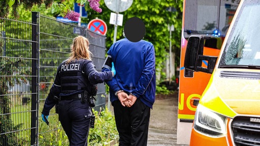Eine Polizistin führt einen Mann in Handschellen ab