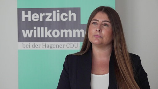 Frau mit langen braunen Haaren steht vor CDU Aufsteller.