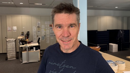 Mann mit grauen kurzen Haaren steht in Redaktion.