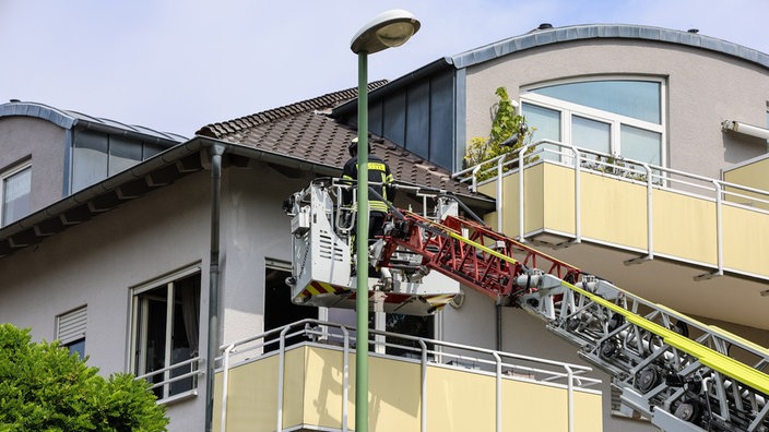 Ausgefahrenes Hubrettungsfahrzeug mit Feuerwehrmann an Wohnung im 2. Stock