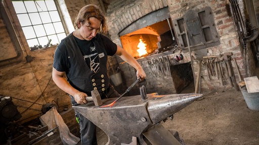 Felix Eckel an einem Amboss, im Hintergrund offenes Feuer