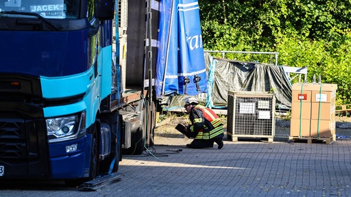 Ein Feuerwehrmann kniet neben einem Lkw und untersucht den Reifen
