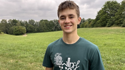 Maxim Akinschin in der Natur. Er lächelt in die Kamera.