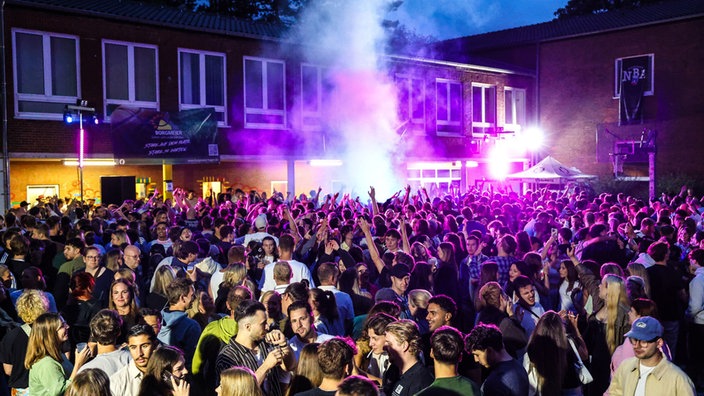 Tausende Menschen feiern am Abend auf einem Schulhof in Hagen.